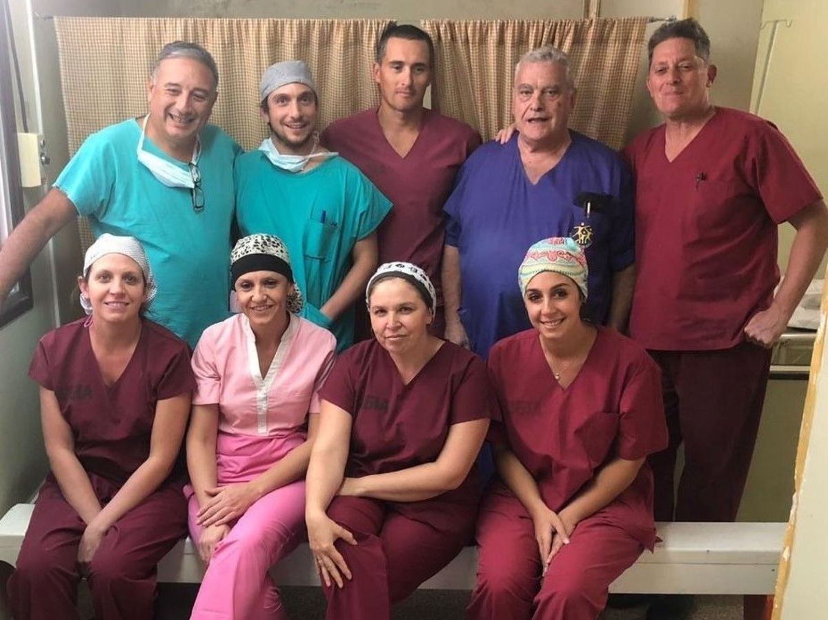 Nueve integrantes del equipo quirúrgico de Caritas Felices, con ambos de colores y gorros de quirófano, posando en el hospital de Choele Choel